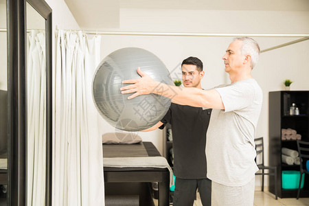 协助老年人在医院里举起运动球的有重背景图片