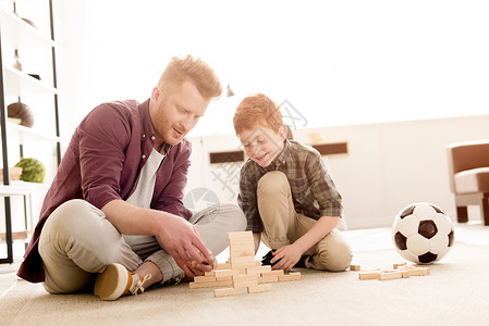 父亲和儿子在家中玩木棍游戏时笑着图片
