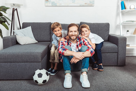 爸笑着和可爱的小儿子们一起在家看足球图片