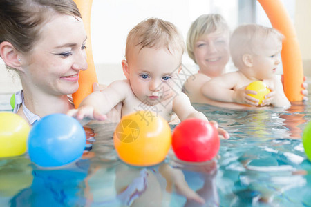 母亲们和孩子在婴儿游泳课上玩得开心在图片