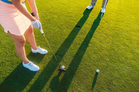 一名女球员和她的搭档拿着推杆高尔夫球杆的高图片