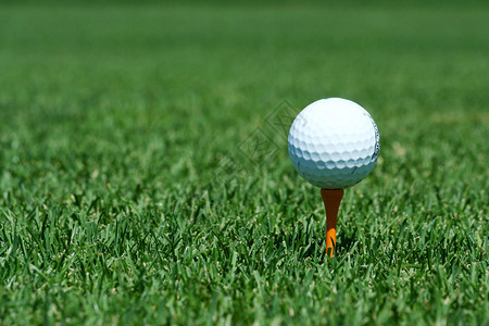 橙色球座上的白色高尔夫球背景图片