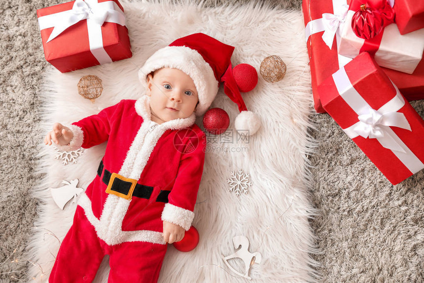 穿着圣诞老人服装和圣诞礼物盒的可爱小宝躺在格子图片
