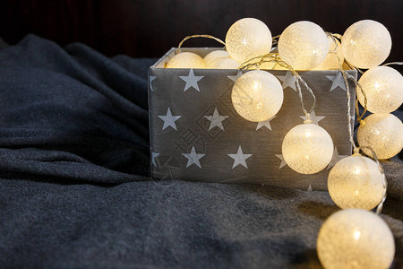 灰色篮子中的白色棉球灯花环与家中闪发光的星背景图片