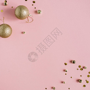 粉红色背景的金色彩蛋和圣诞玩具球图片