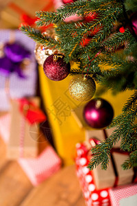 装饰球挂在圣诞树上的礼品盒上图片