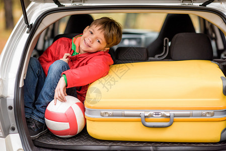 坐在装有球和行李的露天汽车后备箱中图片