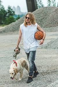 英俊的年轻人带着篮球和狗一起散步图片