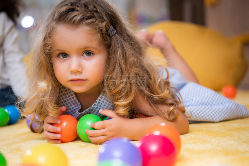 可爱的小孩躺在地毯上幼稚园里带着多彩球图片
