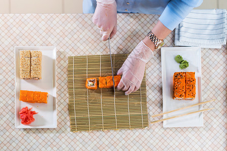 女厨师戴着手套在餐厅制作寿司卷的顶视图图片