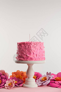 粉红生日蛋糕和蜡烛放在蛋糕摊子上图片