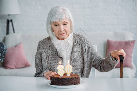 坐在桌边的年老女士生日蛋糕家图片