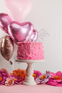 在纸花和灰色心形气球旁的蛋糕摊台上图片