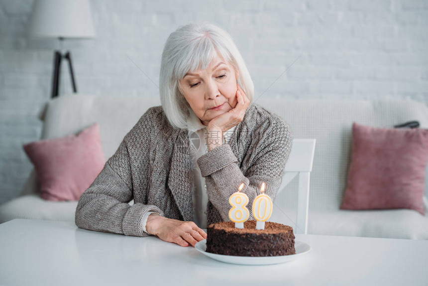 坐在桌边的年老女士生日蛋糕家图片