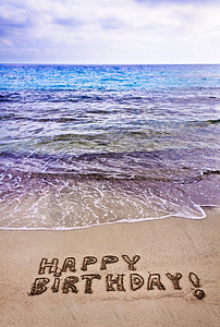 写在沙滩上的生日快乐假期概念图片