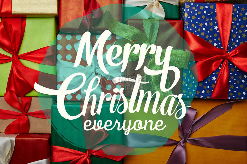 新年礼物包裹在不同的包装纸上木头表面有丝带写着每个人的圣诞快乐的图片