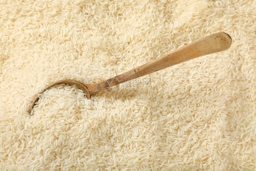 大米背景上的一勺白色长粒米图片