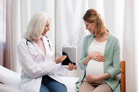 医生在医院向孕妇展示怀孕过程信息图片