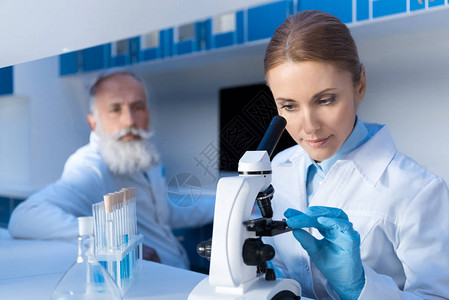 专注的科学家在实验室工作时使用显微镜图片