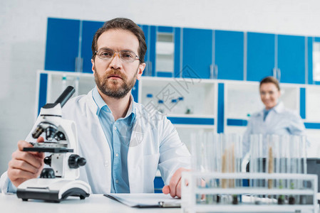 实验室内显微镜的工作场所白大衣和眼镜中的科学家选择焦点图片