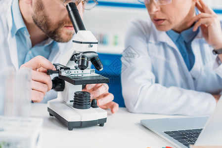 穿着白大褂的科研人员在实验室用显微镜在工作场所一起工图片
