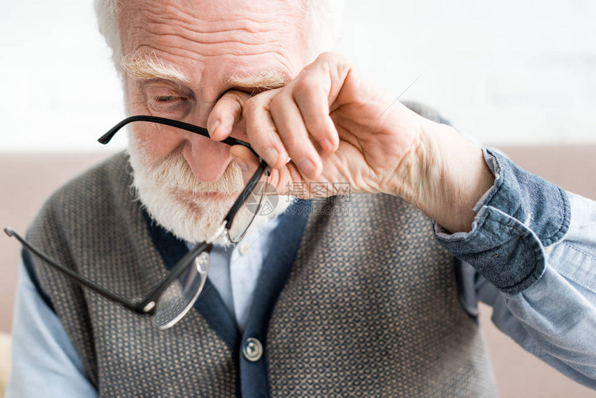 悲伤的老人拿着眼镜用手捂住眼睛图片