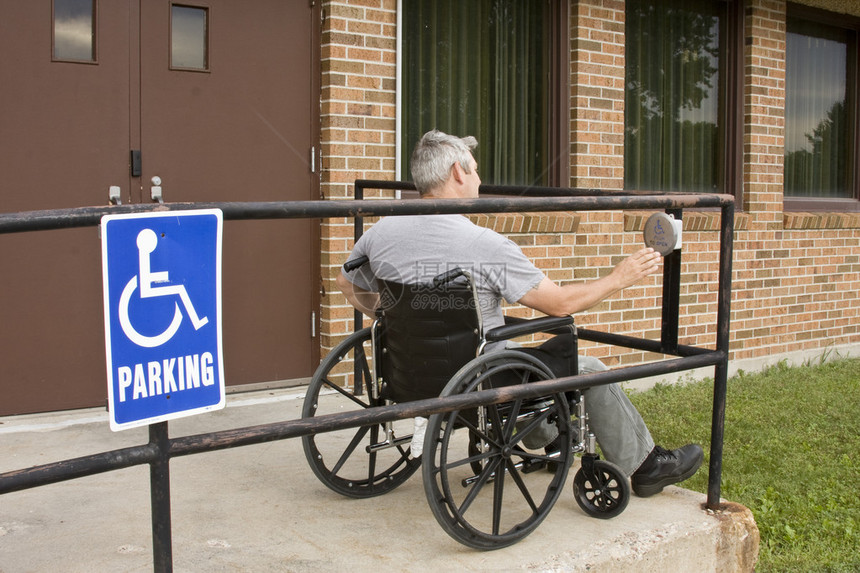 残疾人在轮椅上按残疾人门扣图片