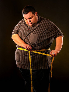 肥仔蚊子男人腹部脂肪与卷尺体重减轻在黑色上的身体周围节食第一背景