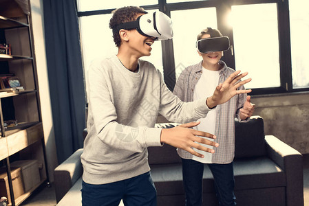 在家里佩戴虚拟现实头盔玩电子游戏概念的青少年图片