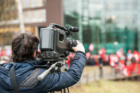 在突发新闻现场活动期间在户外工作的摄像操作员通过其摄像头图片