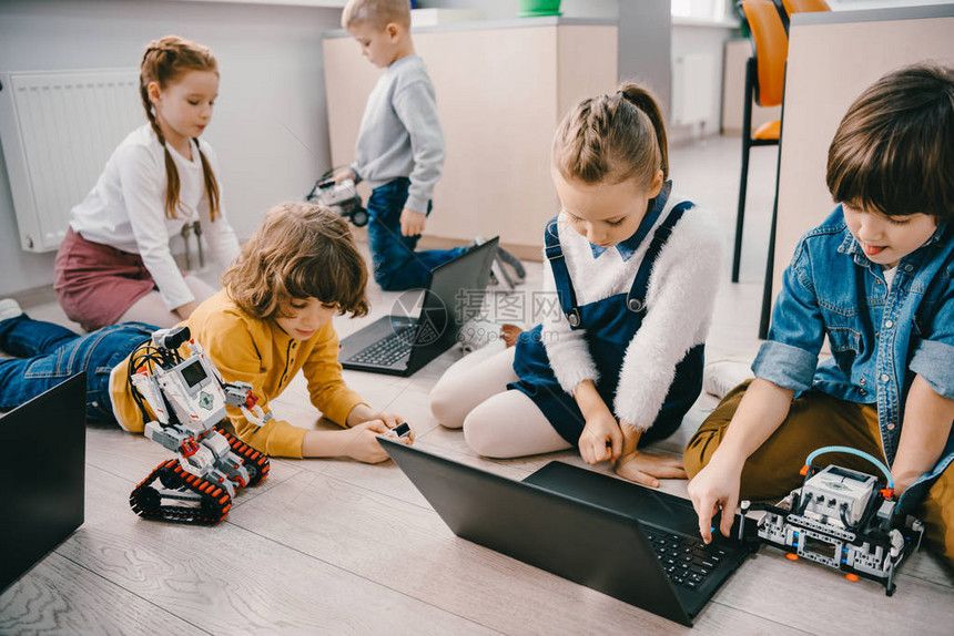 儿童在坐地板上时用笔记本电脑编程didy机器人图片