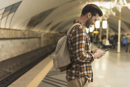 在地铁站用智能手机打背包打字的微图片