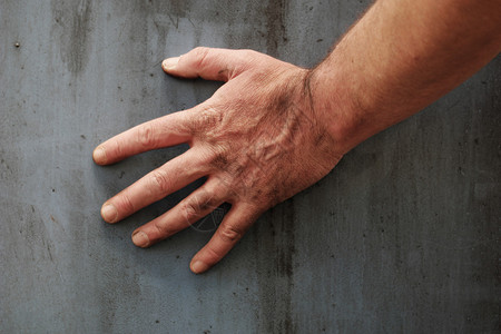 男手触摸着灰土的灰色水泥图片