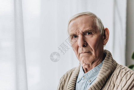 灰白头发的退休老人看着相机心烦意乱图片