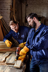 工匠指在木工的电钻工作时与保护手套和谷歌公司合图片