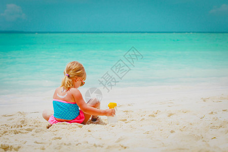 可爱的小女孩正坐在沙滩上玩耍图片