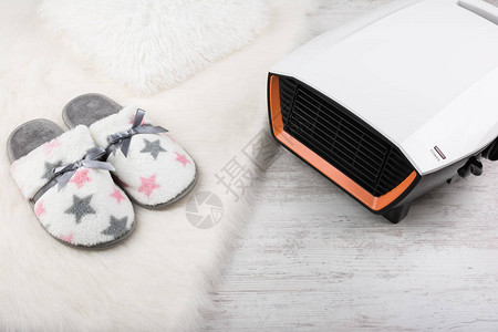 电热器和白色毛地毯上的一双暖拖图片
