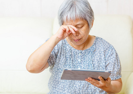 亚洲老年妇女用疲倦的眼睛使用背景图片