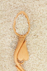 长粒白米放在心形木勺里形成背景图片
