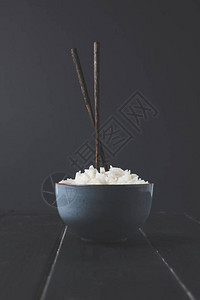 黑桌上的一碗带筷子的新鲜米饭图片