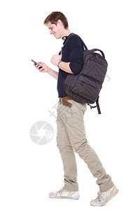 快乐的年轻男学生用手提袋和手机在孤立的白色背景下行走的图片