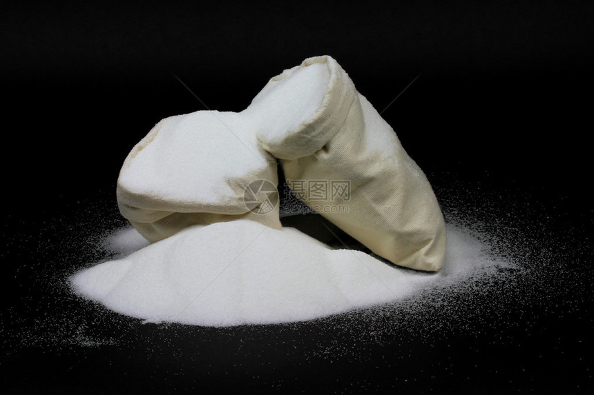 照片来自白色布料袋中的天然颗粒糖在黑背图片