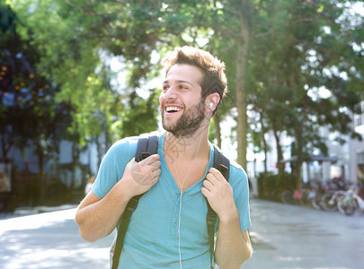 一个带着背包和耳机旅行的快乐年轻人图片