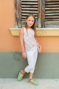 身穿白裤子和绿鞋的可爱时装小女背景图片