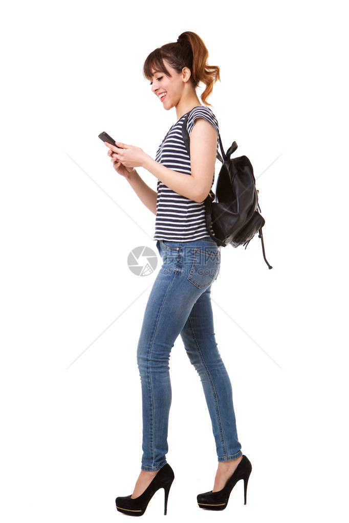 年轻女在白色背景下用手机和包袋行走的图片