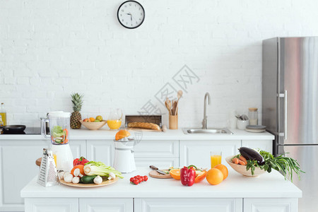 厨房柜台上有美味水果和蔬菜的白色轻白厨房图片