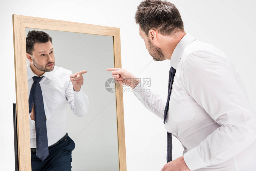 身穿正式服装的超重男子用手指着镜子图片