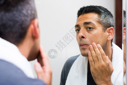 近距离的画面一个男人看着镜子在早上刮胡背景图片