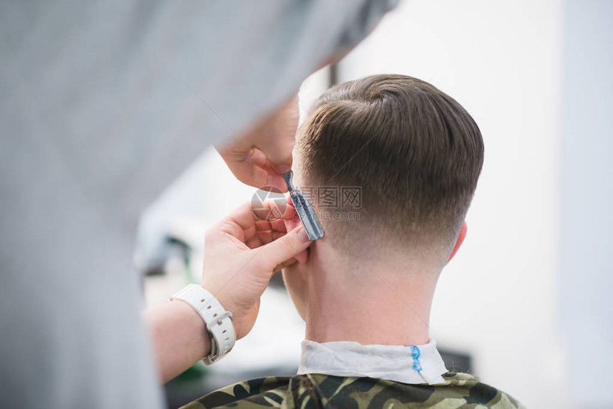 理发师用一把危险的剃须刀剃掉顾客的脖子理发店的男士理发理发师为年轻人图片