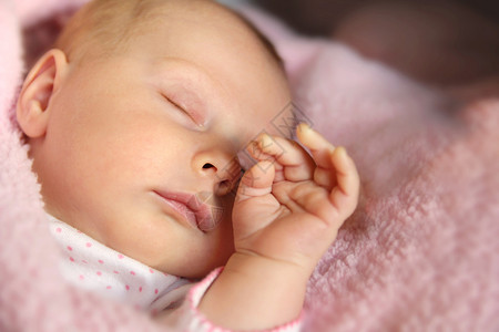 一个可爱的新生的女婴用她的小手背景图片